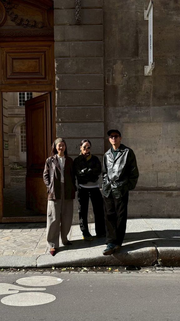 Three members of PHKA, a multidisciplinary floral art collective, standing outside a historic stone building.